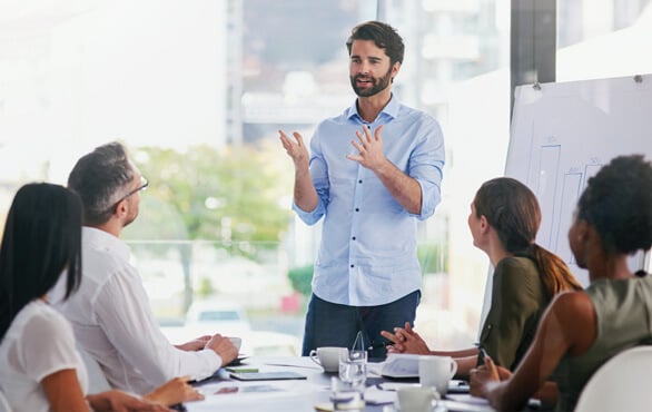 Business professional leading a presentation to colleagues in a meeting, discussing leadership and artificial intelligence strategies for workplace success.