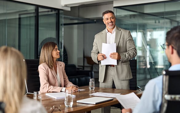 Business leader presenting to team in modern conference room during leadership development training session.