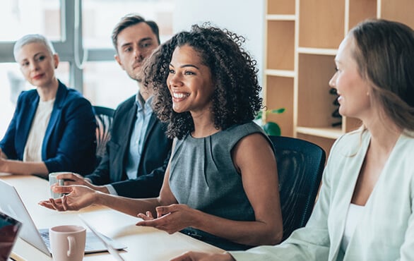 Professional woman leading collaborative discussion with cross-functional team in corporate meeting.