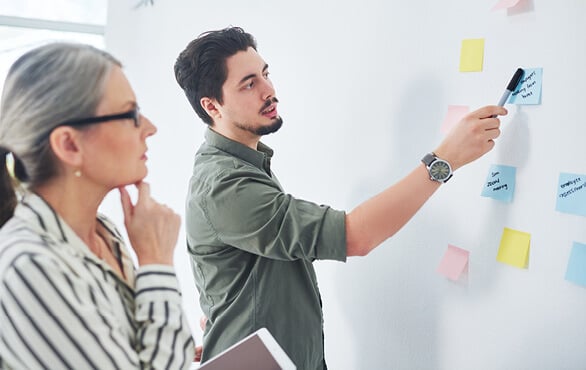 Business professionals collaborating on strategic planning exercise with sticky notes in executive training workshop.