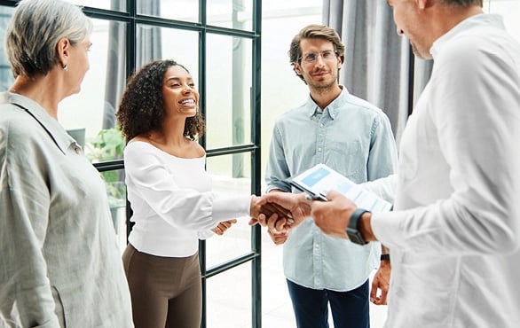 Business professionals greeting one another with a handshake during a workplace networking and collaboration meeting.