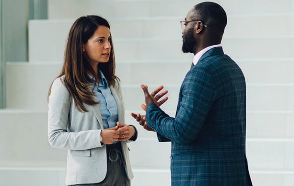 Two professionals engaged in a focused workplace conversation, discussing a challenging business issue face-to-face.
