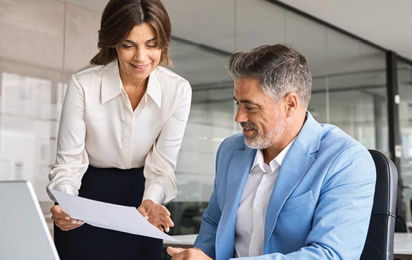 Business professional reviewing financial documents with a colleague during a workplace discussion about budgeting and reporting.