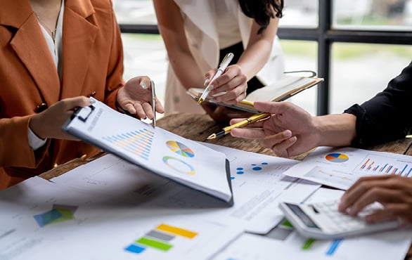 Manager reviewing financial reports and accounting documents with a team member in an office setting