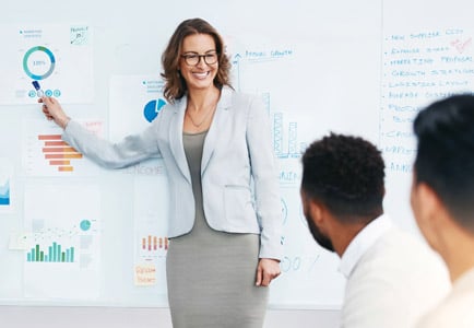 Female leader presenting data strategy on whiteboard, teaching critical thinking and decision-making techniques to team
