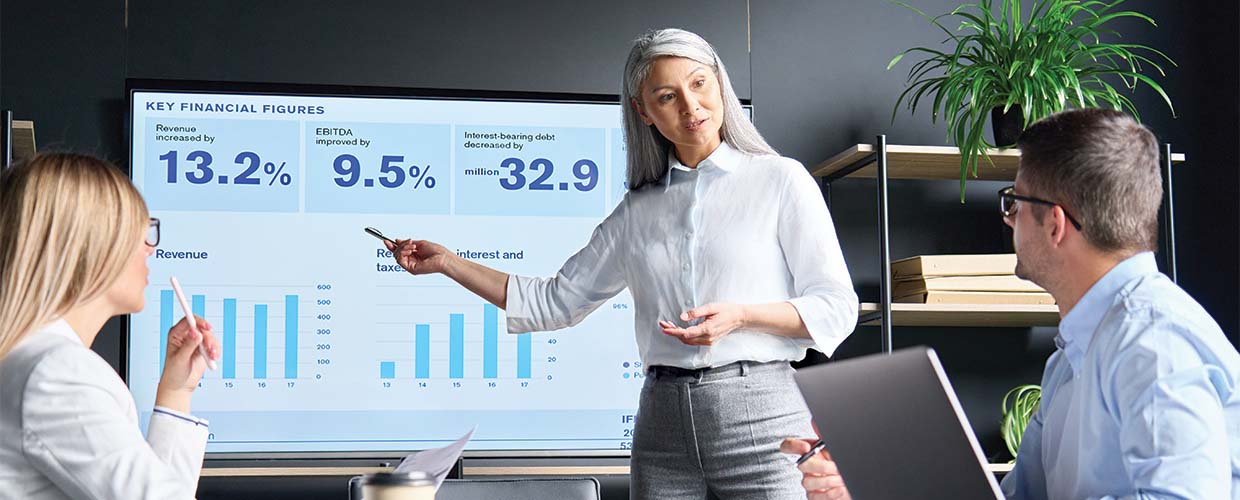 Business leader presenting financial performance data to colleagues during a team meeting about leadership, influence, and organizational alignment.