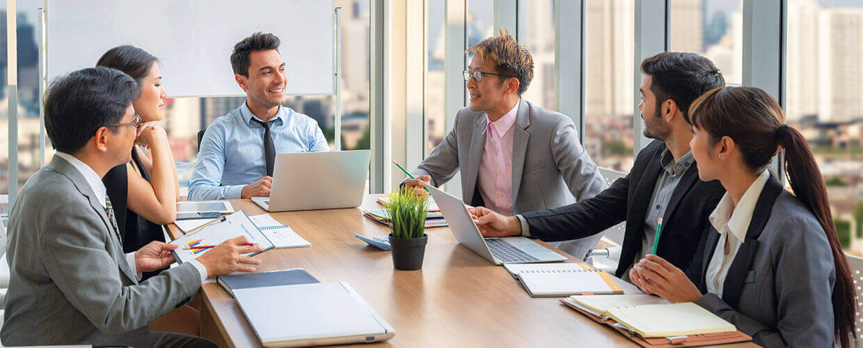 New manager leading a team meeting with colleagues in a modern office, representing the transition from individual contributor to effective leadership through self-awareness.