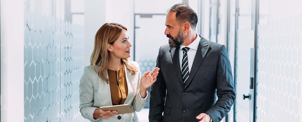 Two business leaders walking through a modern office discussing AI strategy and digital transformation, representing collaboration, leadership and enterprise AI adoption.