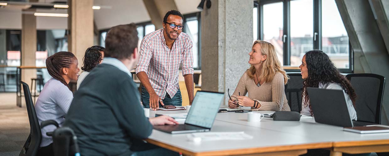Business professionals collaborating during a team meeting as a leader presents ideas, illustrating influence, communication and leadership without formal authority in the modern workplace.
