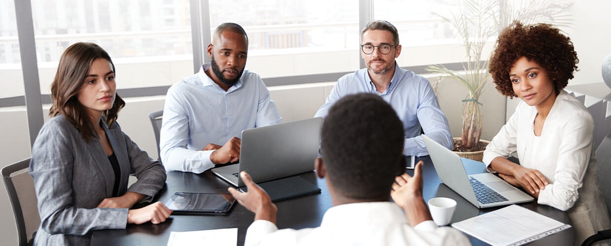 Managers collaborate during a business meeting as a team discusses strategy, decision-making and leadership around a conference table in a modern office.