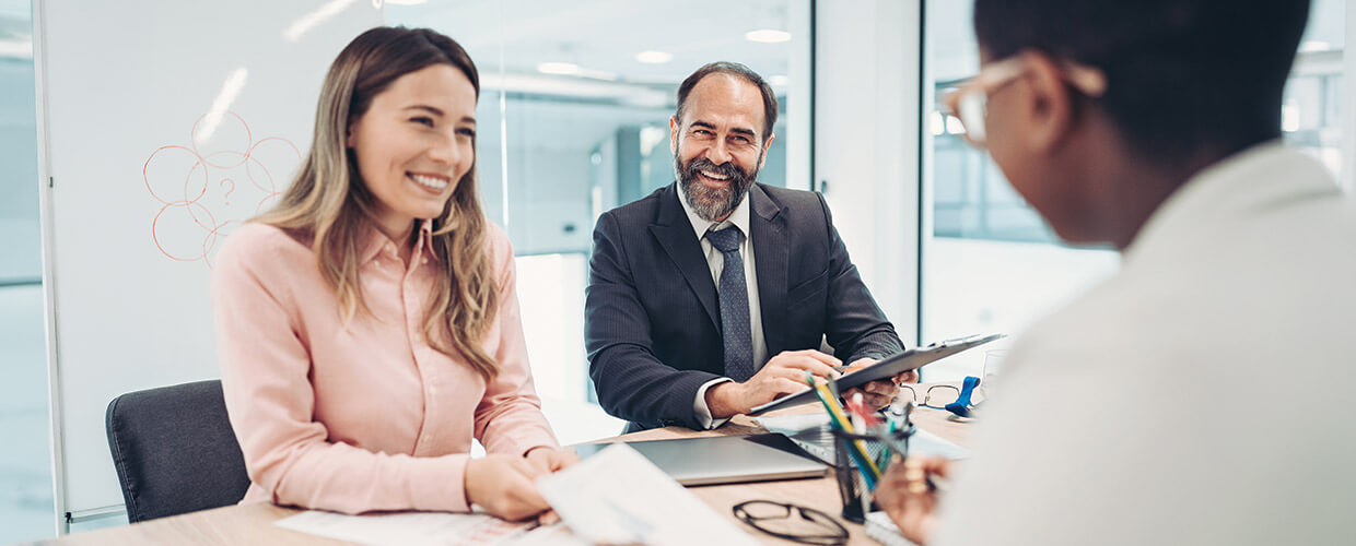 Three professionals discussing documents during a collaborative meeting in a modern office.