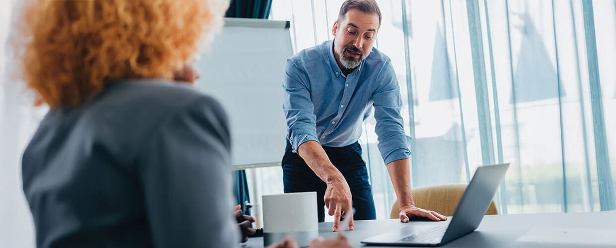 Manager discussing AI-driven work, employee productivity and workplace expectations with a colleague in a modern office.