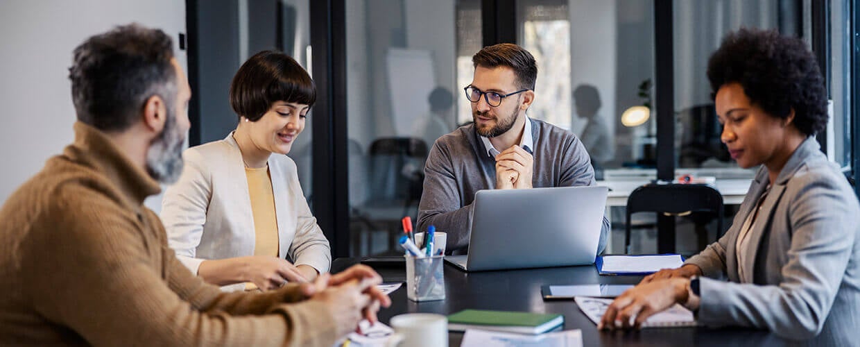 Professionals collaborating in a modern office meeting discussing AI workplace transformation, employee training and the future of work.