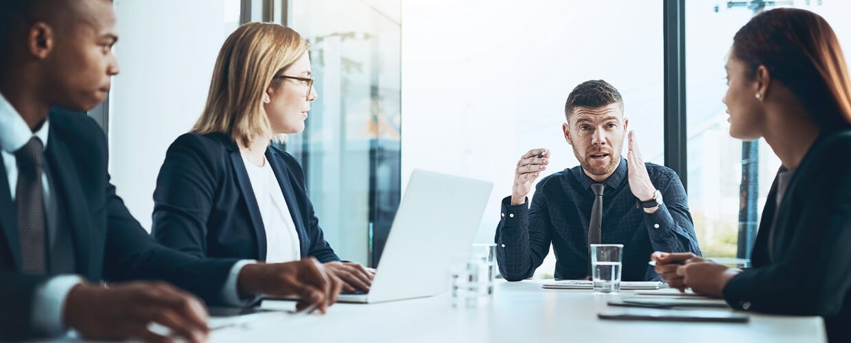 Corporate professionals engaged in a strategic discussion around a conference table.