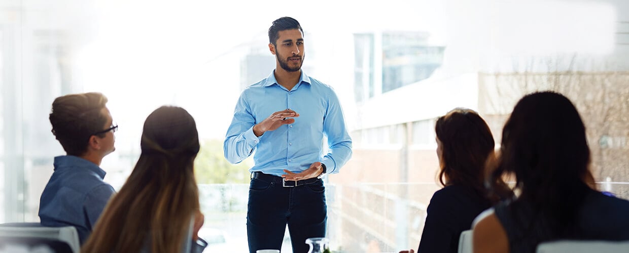 Manager leading a team meeting and explaining change strategy to employees in a modern workplace.