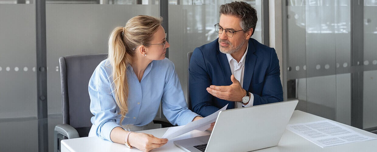Manager coaching employee during a one-on-one meeting in a professional office environment.
