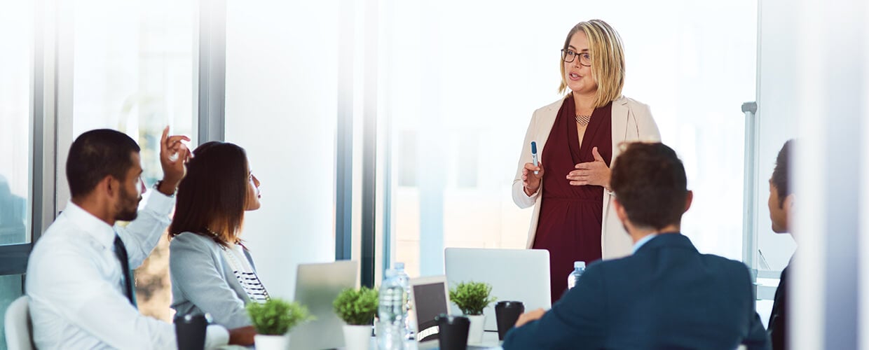 Female leader presenting to a professional team in a modern conference room, highlighting leadership development, team communication, and collaborative decision-making.